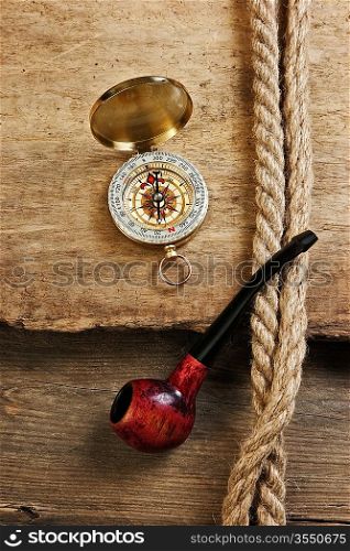 old tobacco pipe and compass on a wooden background