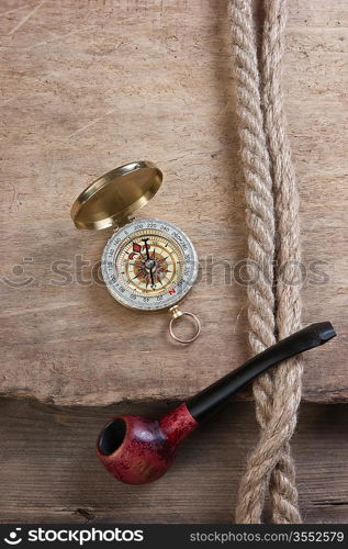 old tobacco pipe and compass on a wooden background