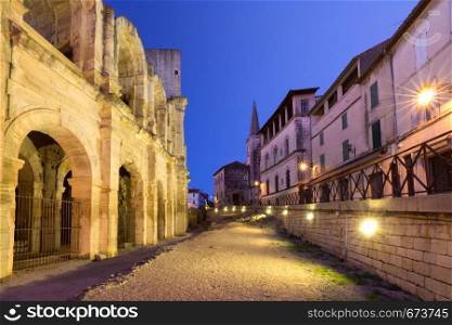 Old town and roman Arles Amphitheatre during evening blue hour, Arles, Provence, southern France. Arles Amphitheatre, France