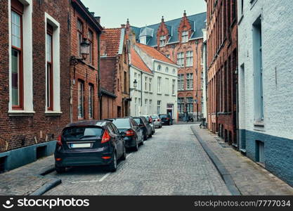 Old town Brugge street with cobblestone road with parked cars and old medieval houses. Bruges, Belgium. Brugge street with cobblestone road with parked cars and old medieval houses. Bruges, Belgium