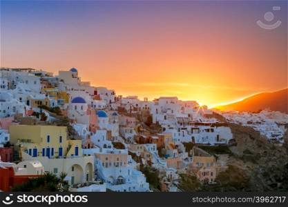 Old Town of Oia on the island Santorini, white houses and church with blue domes at sunrise, Greece