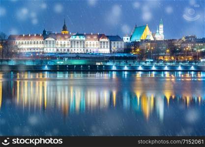 Old Town with reflection in the Vistula River during snowy evening blue hour, Warsaw, Poland.. Old Town and river Vistula at night in Warsaw, Poland.