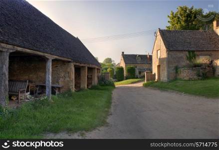 Old traditional English farm at sunset with cart shed and farmhouse.