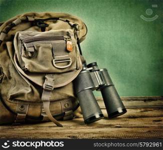 Old travel backpack and binoculars on the floor. Toned