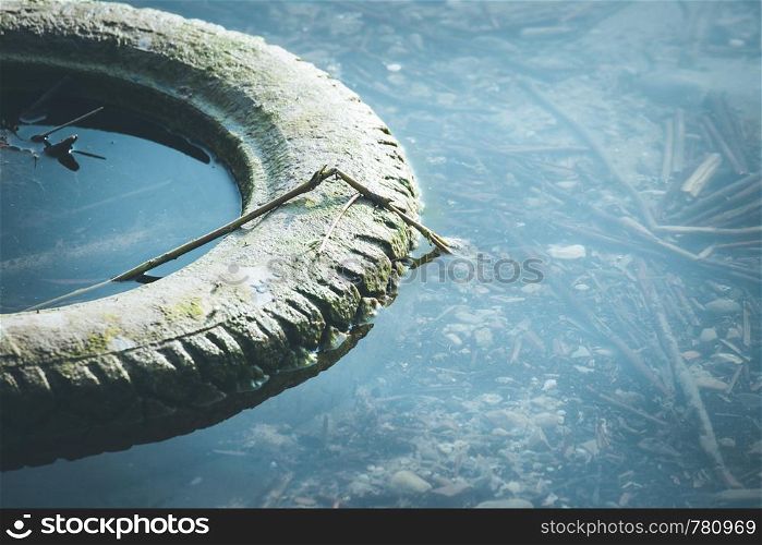 Old tyre is lying in the water, coastline, environmental pollution