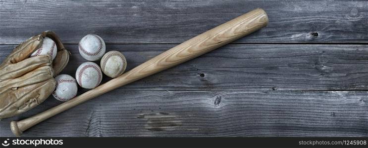 Old used baseballs, bat and weathered glove on vintage wooden background. Baseball sports concept with copy space