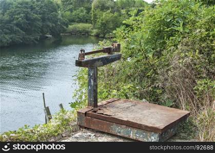 Old used grunge weathered vintage rusty heavy duty weighing scales for fishing use against river background
