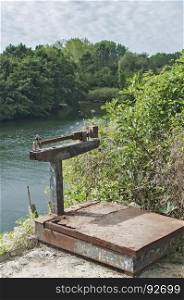 Old used grunge weathered vintage rusty heavy duty weighing scales for fishing use against river background