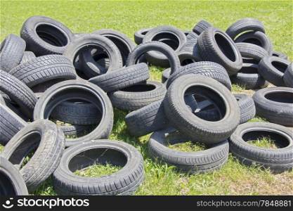 Old used tires stacked on the grass in the park