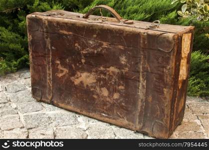 Old used weathered vintage grunge suitcase on stone pavement closeup