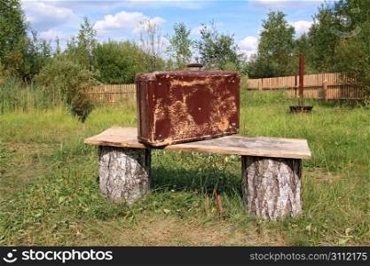 old valise near wooden bench