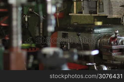 Old vertical drilling machine in workshop. Close up vertical drilling machine and metal plate clamped in bench vise.