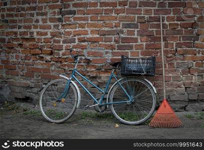 Old village bicycle and plastic hand-rake, near castle wall. 