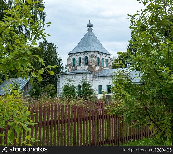 Old village church with painted white walls during restoration and overcast autumn day.. Old brick village Orthodox Church