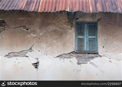 Old vintage house, background texture of a cracked and eroded wall, old bamboo in the ancient cement with cracks, old wooden window, rusty zinc roof. Traditional local house at Luang Prabang, Laos. World Heritage Site.