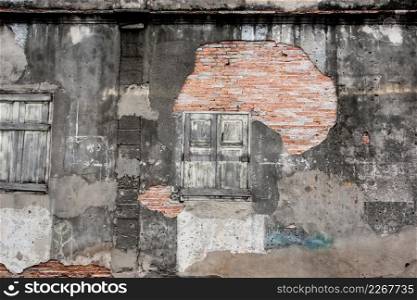 Old vintage house, background texture of a cracked and eroded wall, old bricks in the ancient cement with cracks, old wooden window. Thai Traditional local house at Songkhla, Southern Thailand. Texture. Copy space.