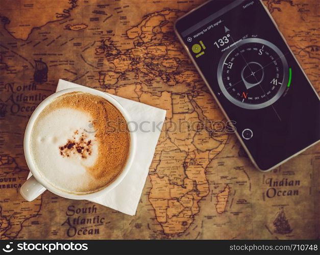 Old, vintage map and mobile phone with a picture of a compass. Top view, close-up. Concept of leisure and travel. Old, vintage map and mobile phone. Top view