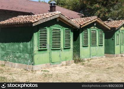 Old vintage obsolete abandoned green wooden camping bungalows in sunny summertime