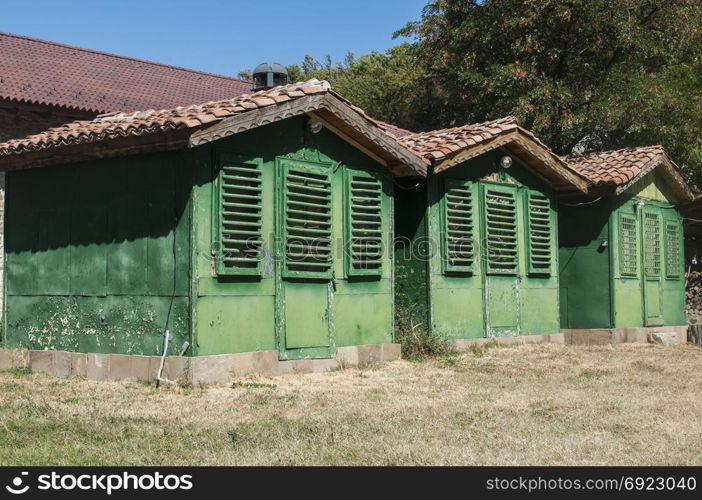 Old vintage obsolete abandoned green wooden camping bungalows in sunny summertime
