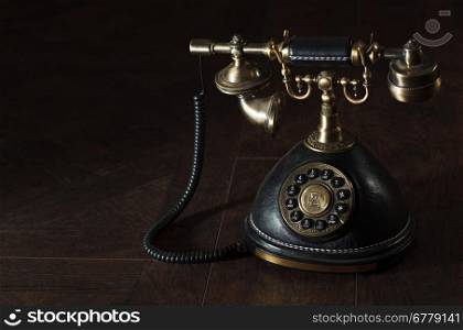 Old vintage or antique rotary phone with a handset and cradle on a dark shadowed background with copyspace