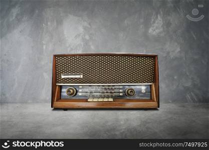 Old vintage retro broadcast radio on cement table with cement background .