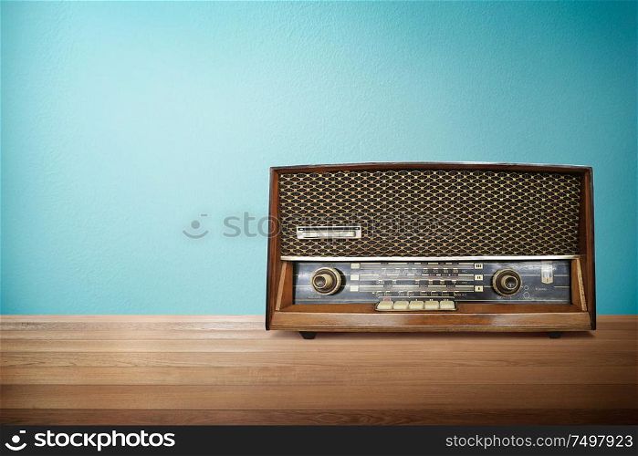 Old vintage retro broadcast radio on wood table with mint blue background .