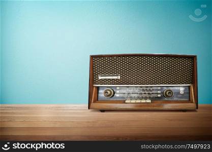 Old vintage retro broadcast radio on wood table with mint blue background .
