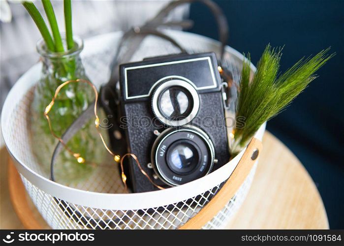 Old vintage rustic camera with a bouquet of daisy flowers on a wooden board. Close-up, bokeh.. Old vintage rustic camera with a bouquet of daisy flowers on a wooden board.