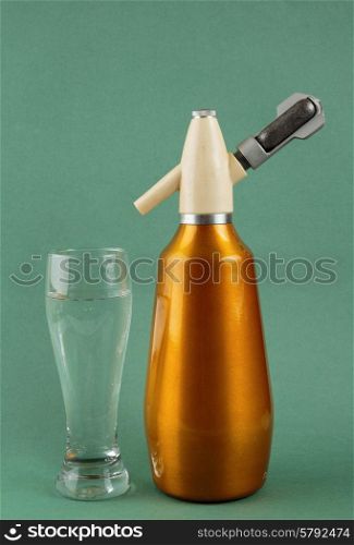Old vintage siphon and glass of water on a green background