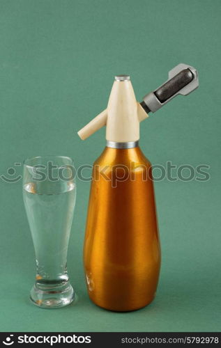 Old vintage siphon and glass of water on a green background