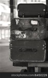 Old vintage suitcases stacked on train railway platform in sepia finish