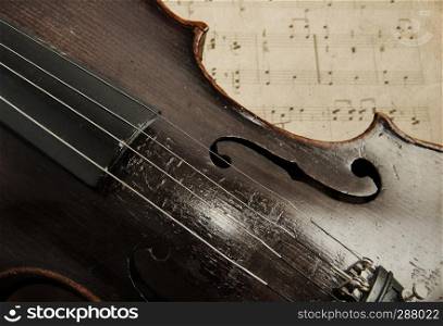 Old violin lying on the sheet of music, music concept