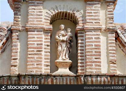 Old virgin sculpture in the facade of a church