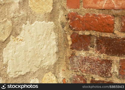 Old wall made of half of stone and red bricks joined by light mortar. Interesting natural background and texture. Horizontal.