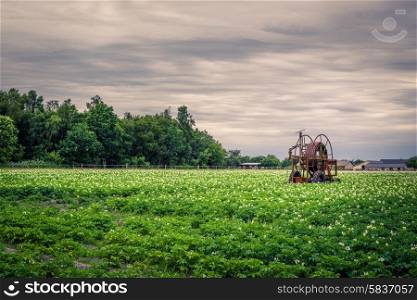 Old water pump on a potato field in cloudy weather