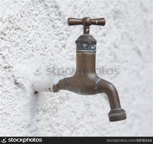 Old water tap on a white wall background