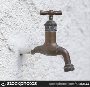 Old water tap on a white wall background