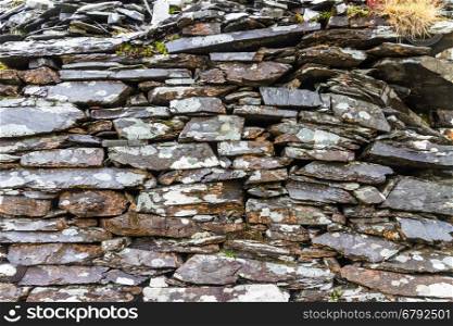 Old weathered dry stone slate wall making background texture