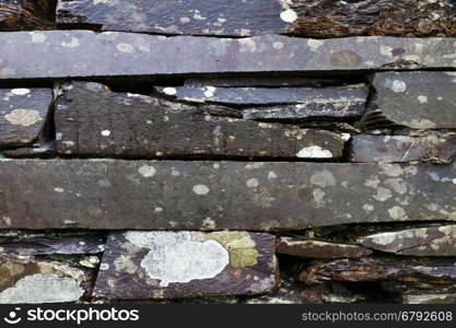Old weathered dry stone slate wall making background texture