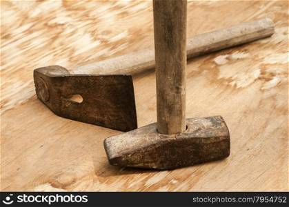 Old weathered grunge hammer and adze head closeup on plywood surface
