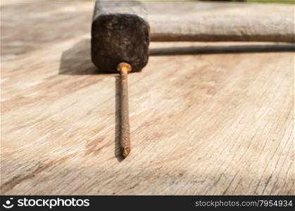 Old weathered grunge hammer and rusty nail on plywood surface as background