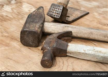 Old weathered grunge hammers and adze head closeup on plywood surface