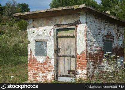 Old weathered grunge solid brick worked farm shed in sunny summer day