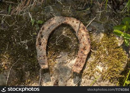 Old weathered rusty iron horseshoe closeup on stone background