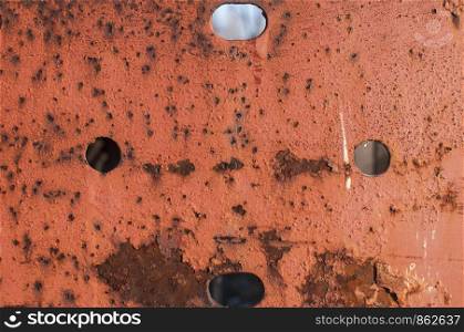 Old weathered rusty iron plank surface with holes closeup as grunge background