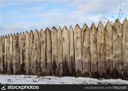 Old weathered wooden fence in the village, winter time