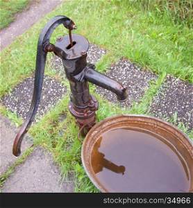 old wet cast iron water pump in garden and zinc tub