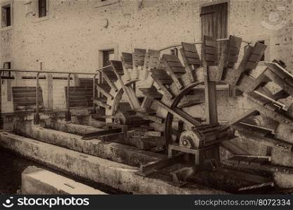Old wheels of a watermill. Vintage style picture. Adding grain to give an old photo effect.