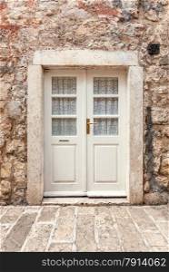 Old white classic door in ancient stone building