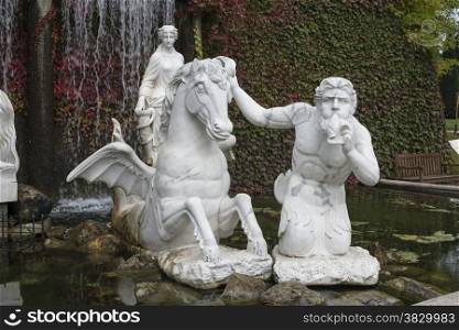 old white roman marrble sculptures like pegasus in italian garden